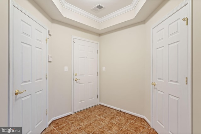 entryway with ornamental molding, a tray ceiling, visible vents, and baseboards