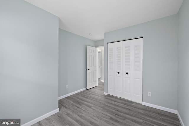 unfurnished bedroom featuring a closet, baseboards, and wood finished floors