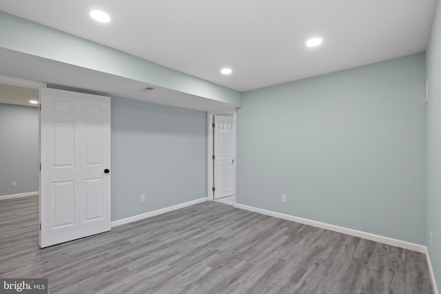 finished below grade area with light wood-style floors, recessed lighting, visible vents, and baseboards