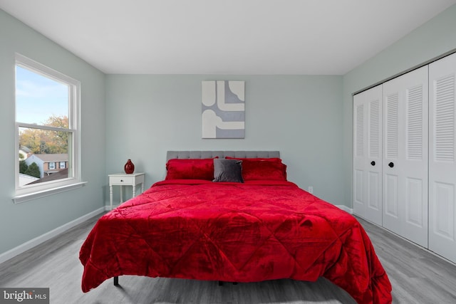 bedroom with light wood-type flooring, a closet, and baseboards