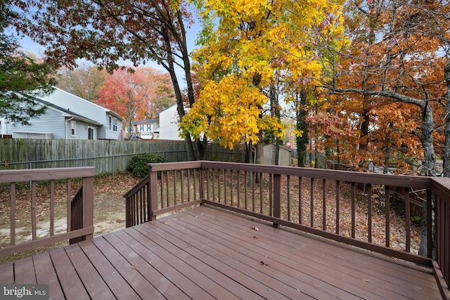 wooden deck with a storage unit, an outdoor structure, and a fenced backyard