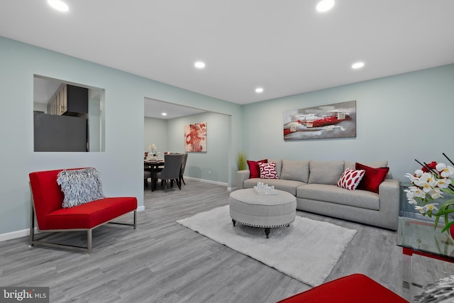 living area with baseboards, light wood-type flooring, and recessed lighting