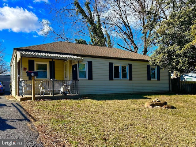 view of front facade featuring covered porch, a shingled roof, and a front lawn