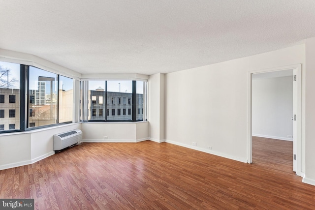 spare room featuring radiator heating unit, a textured ceiling, baseboards, and wood finished floors