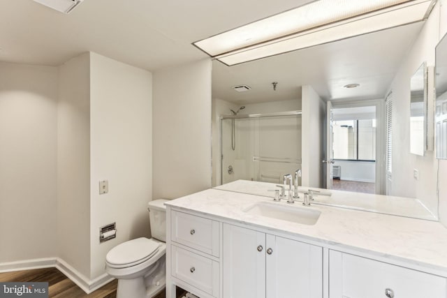 bathroom with toilet, wood finished floors, vanity, baseboards, and a shower stall