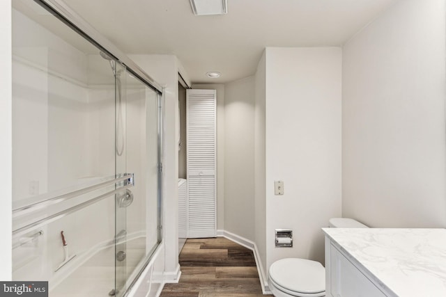 full bathroom with enclosed tub / shower combo, toilet, wood finished floors, vanity, and baseboards