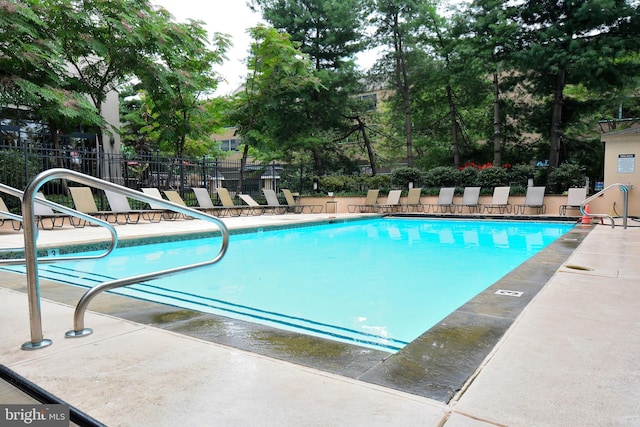 pool with a patio area and fence