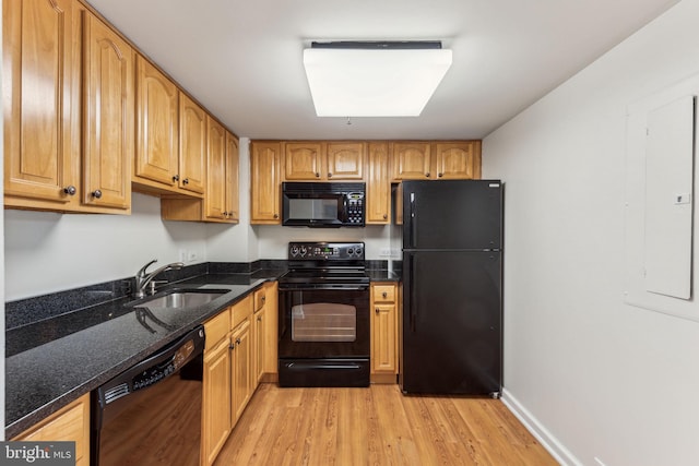 kitchen featuring a sink, light wood-style floors, electric panel, dark stone counters, and black appliances