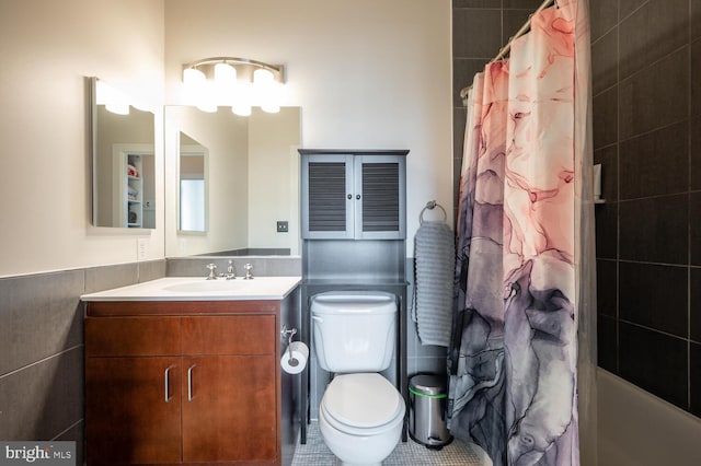 bathroom with toilet, wainscoting, tile walls, and vanity