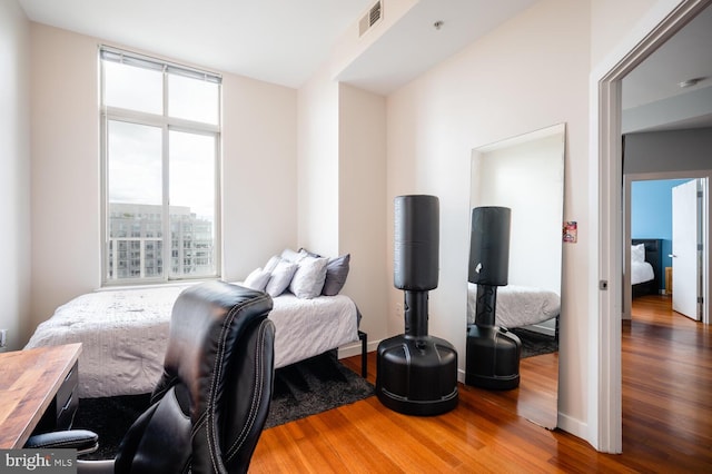 bedroom with a view of city, visible vents, and wood finished floors