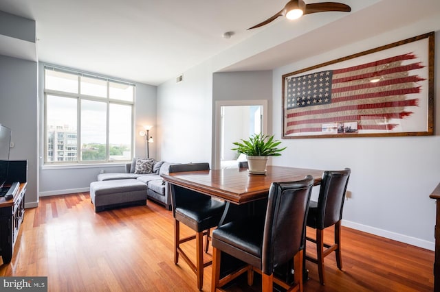 dining area featuring a ceiling fan, visible vents, baseboards, and wood finished floors