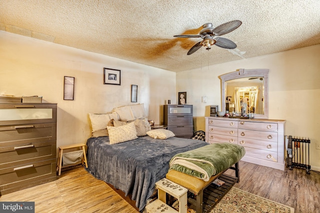 bedroom featuring radiator, a textured ceiling, a ceiling fan, and wood finished floors