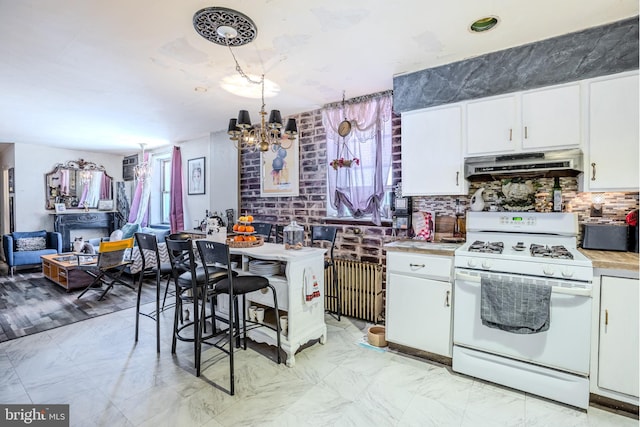 kitchen featuring under cabinet range hood, white gas range oven, white cabinets, and light countertops