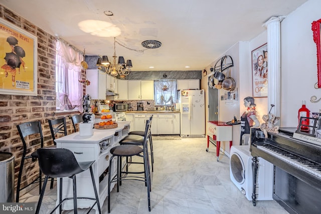 kitchen with a chandelier, under cabinet range hood, white cabinets, marble finish floor, and white fridge with ice dispenser