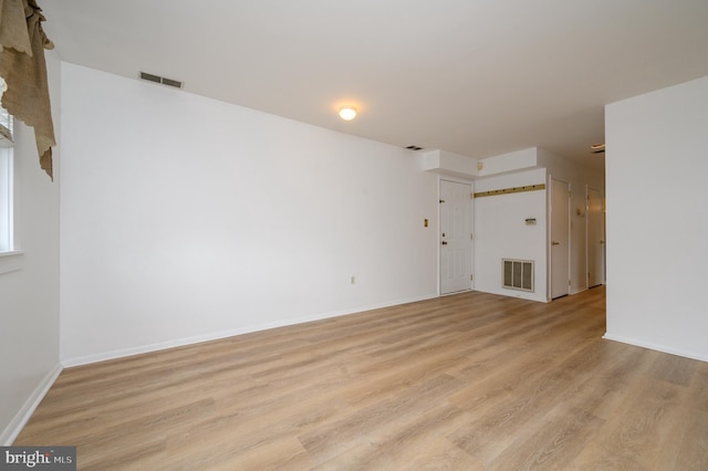 unfurnished living room featuring baseboards, visible vents, and light wood-style floors