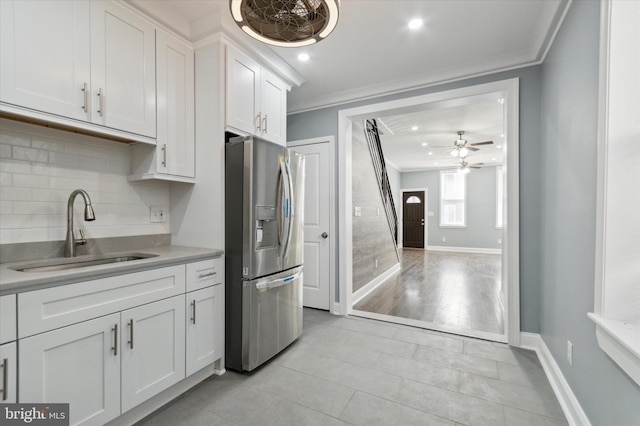 kitchen with a sink, white cabinets, light countertops, stainless steel fridge, and crown molding