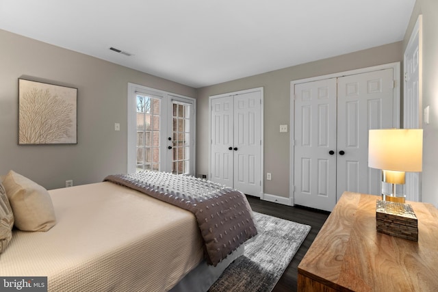 bedroom with visible vents, access to outside, french doors, dark wood-style floors, and two closets