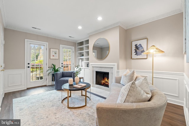 living area featuring visible vents, built in features, dark wood-style floors, crown molding, and a high end fireplace