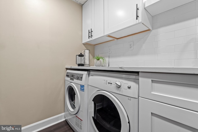 washroom featuring dark wood-style flooring, washing machine and dryer, cabinet space, and baseboards