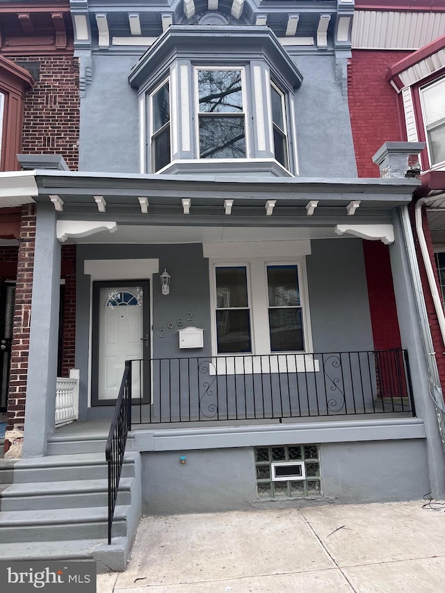 view of front of property featuring covered porch, stucco siding, and brick siding