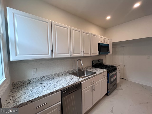 kitchen with a sink, white cabinetry, marble finish floor, appliances with stainless steel finishes, and light stone countertops