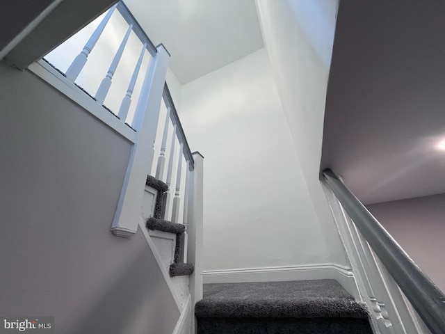 stairway featuring a towering ceiling and baseboards