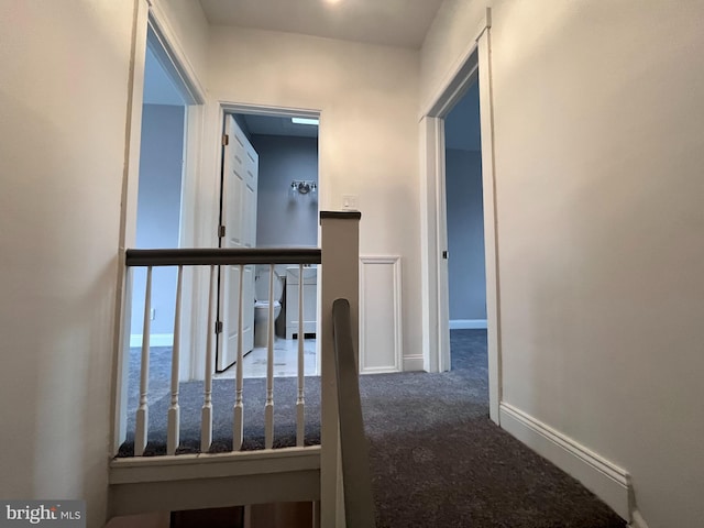 hallway with baseboards, carpet flooring, and an upstairs landing