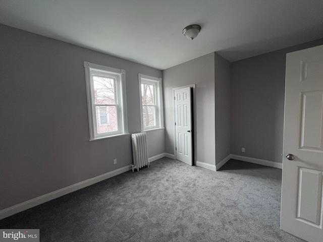 unfurnished bedroom featuring carpet, radiator, and baseboards