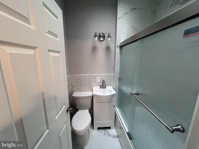 full bath with marble finish floor, a shower with door, tile walls, toilet, and vanity