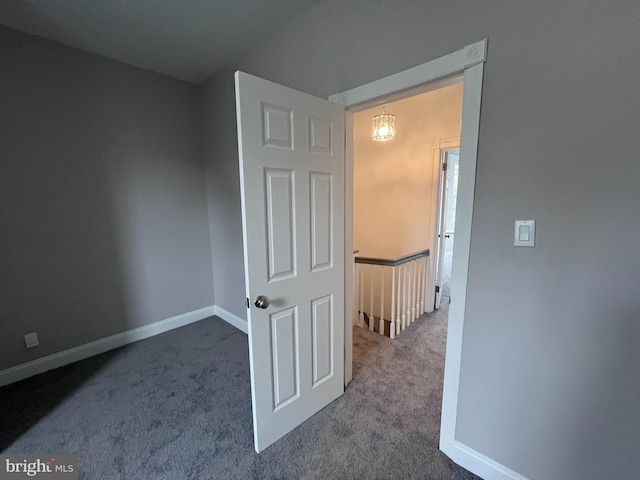 hall featuring baseboards, carpet flooring, and an upstairs landing