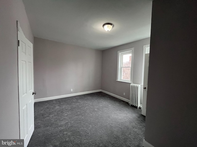 interior space featuring radiator, baseboards, and dark colored carpet