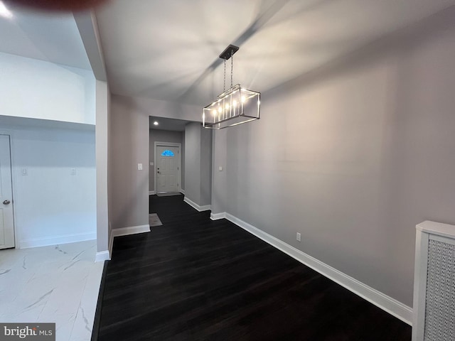 unfurnished dining area featuring dark wood finished floors and baseboards