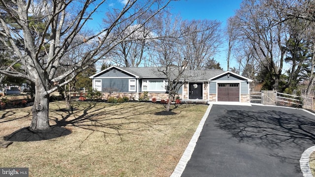 single story home featuring aphalt driveway, a garage, fence, stone siding, and a front lawn