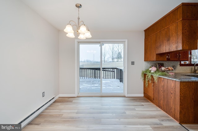 unfurnished dining area with a baseboard radiator, a sink, baseboards, light wood finished floors, and an inviting chandelier