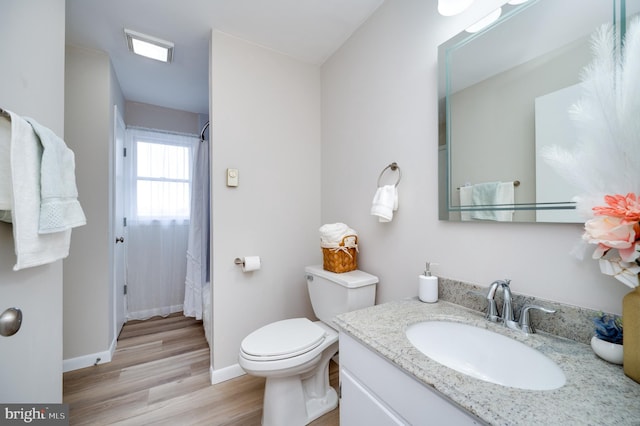 bathroom with toilet, baseboards, wood finished floors, and vanity