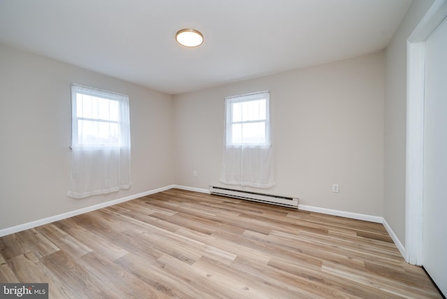 spare room with baseboards, light wood finished floors, and baseboard heating