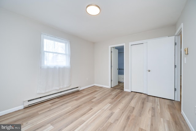 unfurnished bedroom featuring a baseboard heating unit, a closet, light wood-style floors, and baseboards