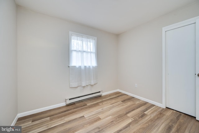 unfurnished room with light wood-style flooring, a baseboard heating unit, and baseboards