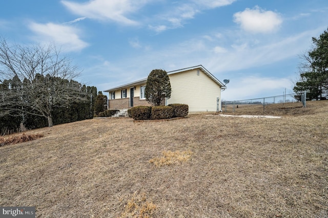 view of side of home featuring fence, a lawn, and brick siding