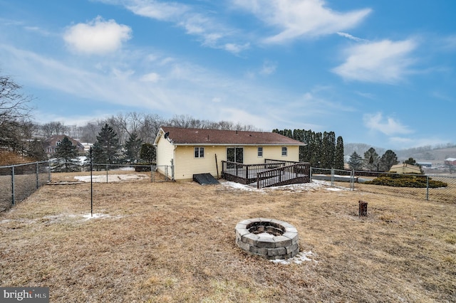 back of house featuring a fenced backyard, a fire pit, and a deck