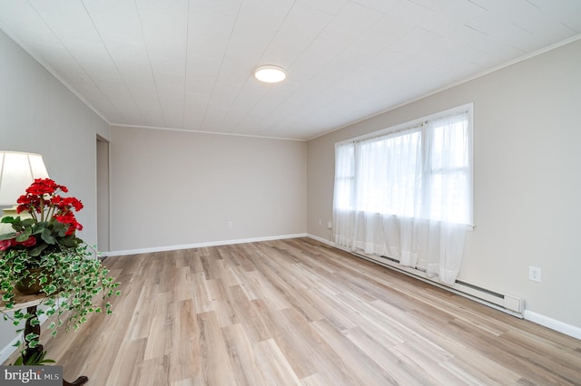 empty room with a baseboard heating unit, crown molding, light wood-style flooring, and baseboards