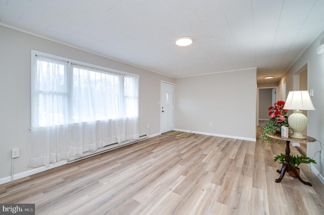 interior space with light wood-style flooring, baseboards, baseboard heating, and ornamental molding