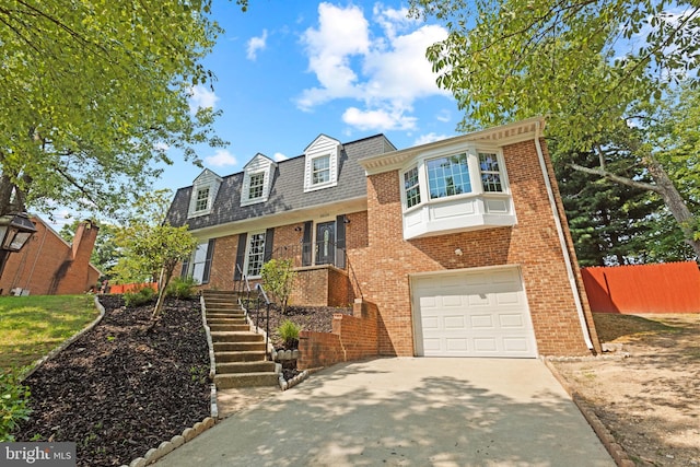 view of front facade with an attached garage, fence, concrete driveway, and brick siding