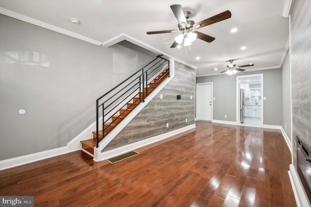 interior space with dark wood-type flooring, visible vents, crown molding, and stairs