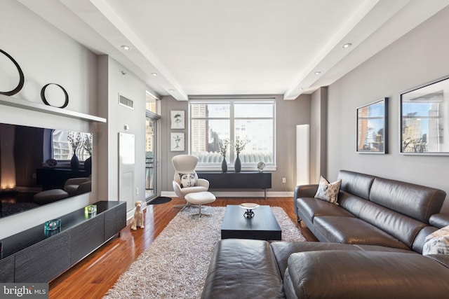 living room with wood finished floors, visible vents, and baseboards