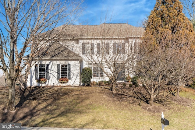 colonial home featuring a front yard and roof with shingles