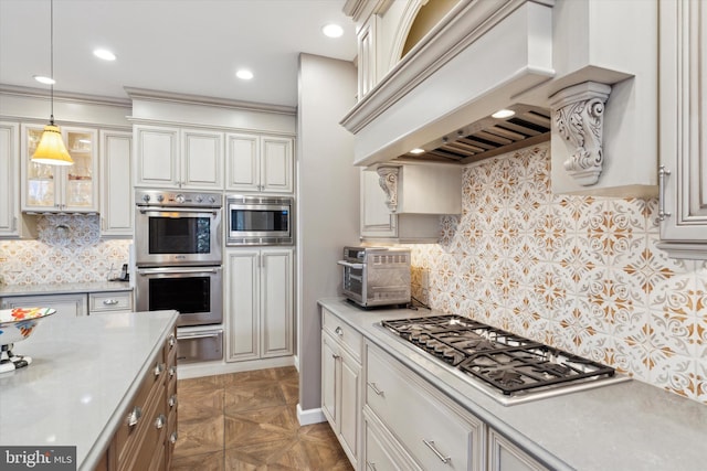 kitchen featuring custom range hood, decorative light fixtures, stainless steel appliances, light countertops, and backsplash