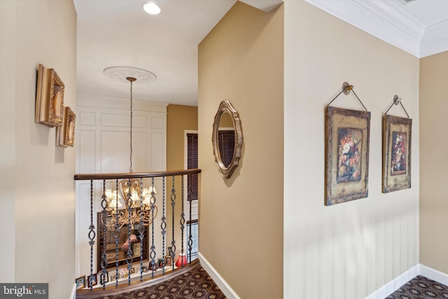 corridor with an inviting chandelier, baseboards, and crown molding