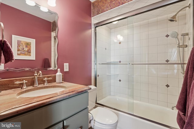 bathroom with toilet, shower / bath combination with glass door, and vanity