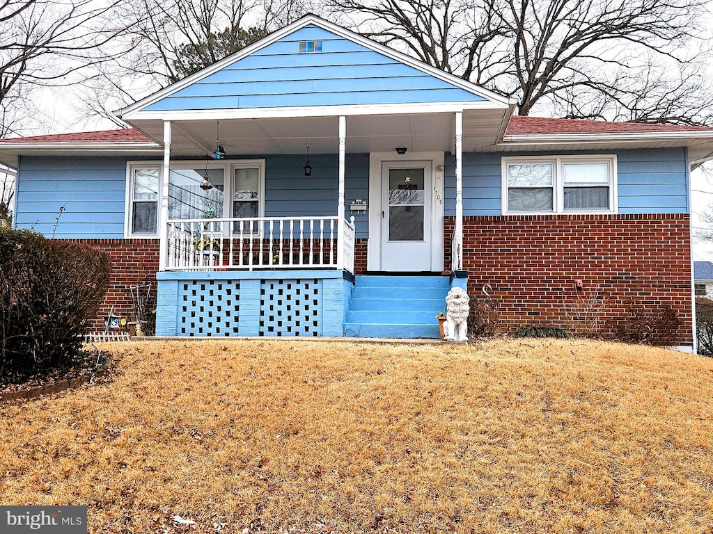 bungalow-style home featuring a porch, brick siding, and a front lawn